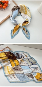 Detail eines plissierten Seidenschals mit gelbem Pferdemuster und geometrischem Design