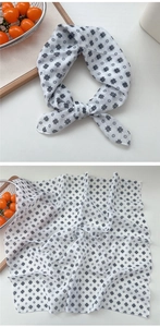 Detail of white cotton linen scarf with black floral print and stylish knotted texture