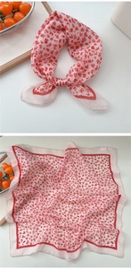 Detail showing soft pink square scarf with red floral pattern and smooth texture