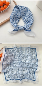 Detail showing the floral print cotton linen scarf with blue geometric border and label