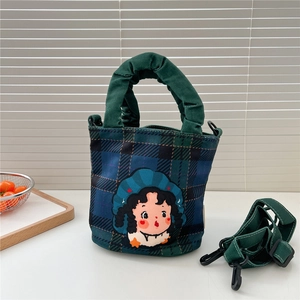 Détail du sac en toile à carreaux vintage avec patch cartoon et anse verte plissée