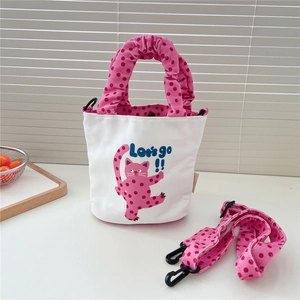 Détail d'un petit sac seau en toile avec motif chat et bandoulière rose à pois
