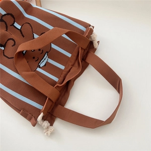 Detail view of knitted tote bag with brown blue stripes and cute cartoon bear pattern