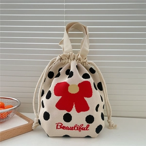 Detail of knitted drawstring handbag with polka dots and red flower embroidery