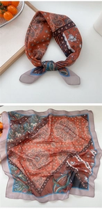Detail of paisley floral square scarf showing texture and knotting in rust red and brown