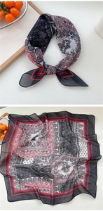 Detail of a square paisley scarf showing soft breathable fabric and red hemmed edges