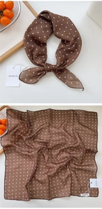 Detail of a dark brown polka dot cotton linen neck scarf with brand tags shown on a white table
