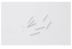 Macro shot of silver stud earrings needles and minimalist metal pins on white background