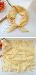 Macro detail of yellow cotton linen scarf with blue polka dots and neat rolled edges