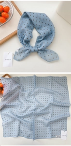 Close-up of light blue cotton linen scarf with dark brown polka dots and soft texture