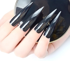 Détail de longs faux ongles stiletto noirs avec une finition miroir chromée brillante