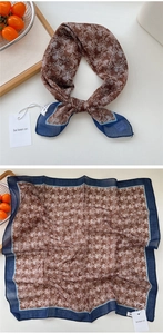 Close-up of a Baroque printed square scarf in brown and navy blue on a white surface