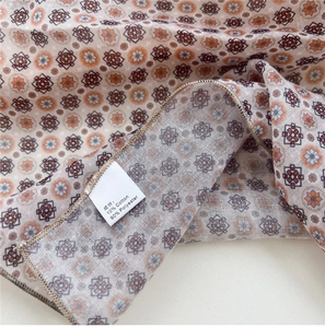 Macro detail of polka dot cotton-linen scarf showing the care label and geometric patterns