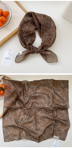 Detailed texture of brown paisley silk-feel square scarf with elegant knotted styling