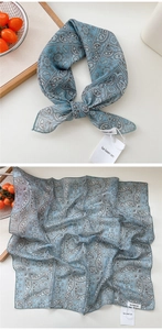 Detail of light blue paisley cotton silk scarf showing brand tag and textile texture