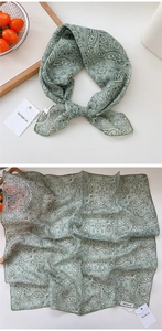 Detailed close-up of green paisley silk scarf with delicate stitching and pattern