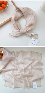 Close-up of beige polka dot cotton linen scarf showing soft texture and brand tag