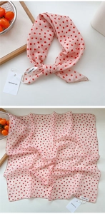 Detail of light pink polka dot silk scarf showing fabric texture and edge stitching