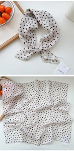 Macro detail of creamy white polka dot scarf with soft texture and refined stitching