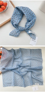 Detailed view of light blue polka dot cotton-linen scarf with brand tags on wooden tray