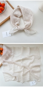 Close-up of cream polka dot linen silk scarf showing natural texture and brand tag