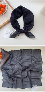 Detailed close-up of a black polka dot silk scarf on a wooden tray with sheer fabric texture