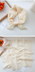 Detailed macro view of cream square scarf with yellow polka dots on a wooden tray