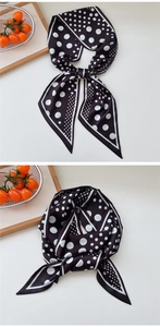 Detailed view of polka dot silk scarf in black and white tied as a decorative bow