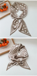 Detail of champagne satin scarf with classic white polka dots and elegant French bow style