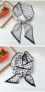 Detail of a narrow silk scarf with black and white paisley and polka dot patterns