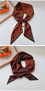 Detail of silk-feel scarf with orange and brown paisley and houndstooth patterns
