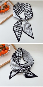 Detail of a black and white paisley and houndstooth silk scarf tied in a stylish knot