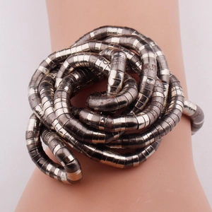 Macro shot of flexible silver-toned coiled snake bracelet showing intricate metallic texture