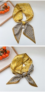 Detail of paisley and geometric patterns on a yellow silk neck scarf with brown edges