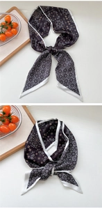 Detail view of paisley print skinny silk scarf tied neatly on a minimalist white background