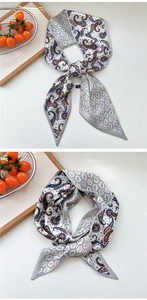 Detail of paisley silk skinny scarf with maroon and navy patterns on beige silk texture