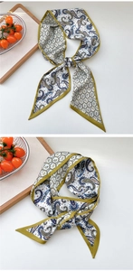 Detailed view of paisley and geometric pattern silk scarf with green border