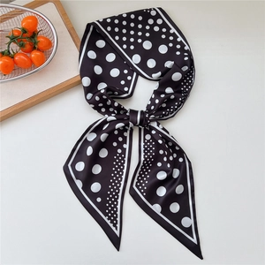 Silk satin skinny scarf featuring black and white polka dots tied in an elegant bow