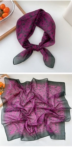 Detailed view of floral silk scarf showing soft purple fabric texture and black borders