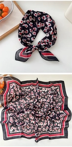 Detail view of square floral scarf with white petals and red stripe border on black silk