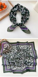 Close-up of dark green floral silk scarf showing delicate patterns and decorative knot
