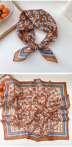 Close-up of orange floral square scarf with geometric borders and lightweight texture
