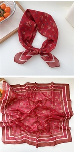 Detail view of red floral silk scarf showing delicate flower patterns and white borders