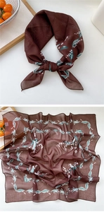 Detail of silk square scarf featuring lily of the valley floral print on deep brown fabric