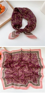 Detail view of burgundy floral silk square scarf with vintage border on wooden tray