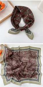 Detail of floral silk scarf with dark red patterns and striped edges shown on a wooden tray