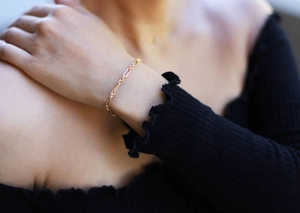 Detail shot of a minimalist gold plated chain bracelet worn on a woman's wrist