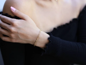 Detailed close-up of a gold-plated link chain bracelet worn on a woman's wrist