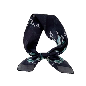 Navy blue silk scarf with lily of the valley floral pattern tied in a soft bow knot