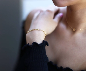 Detailed view of simple gold chain bracelet with round links worn on a female wrist